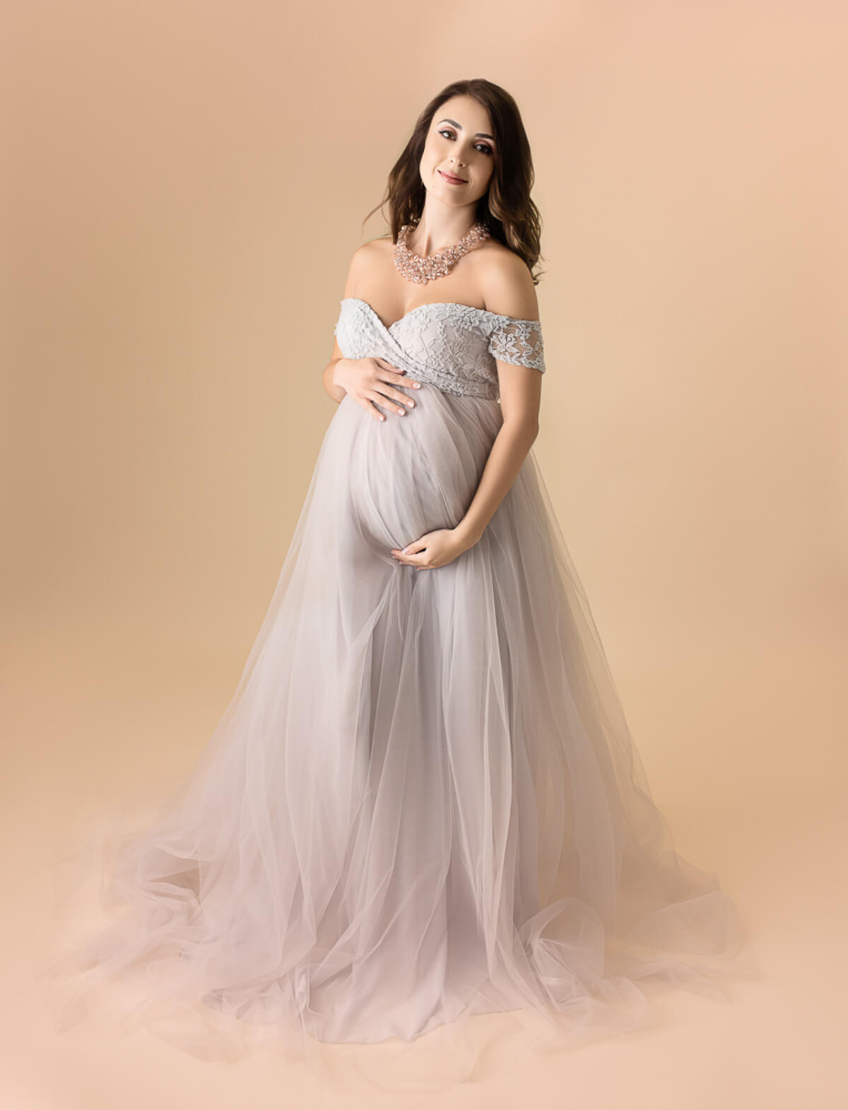 Pregnant woman in a long gown holding her bum in a maternity photo