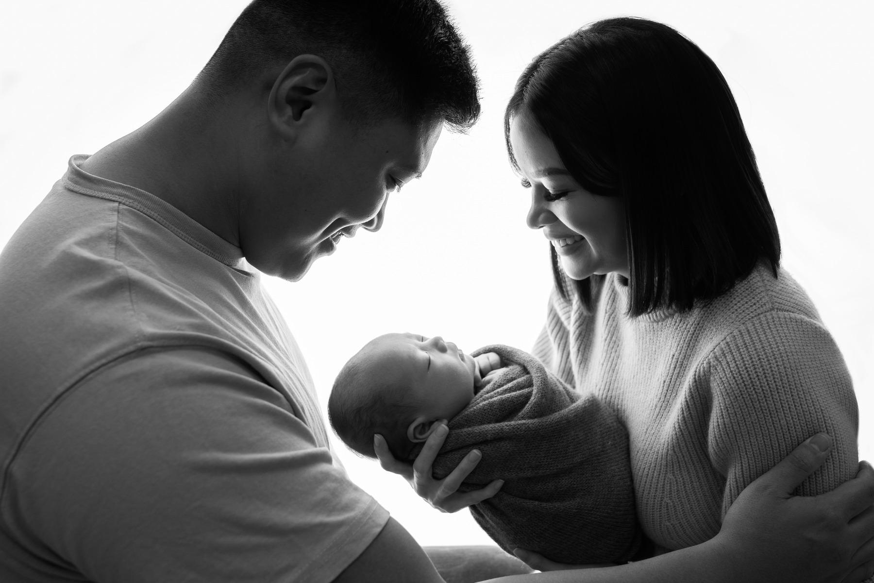 "New parents holding their baby in a black and white photo, captured by Céire Rhein, Dublin's newborn photographer."
