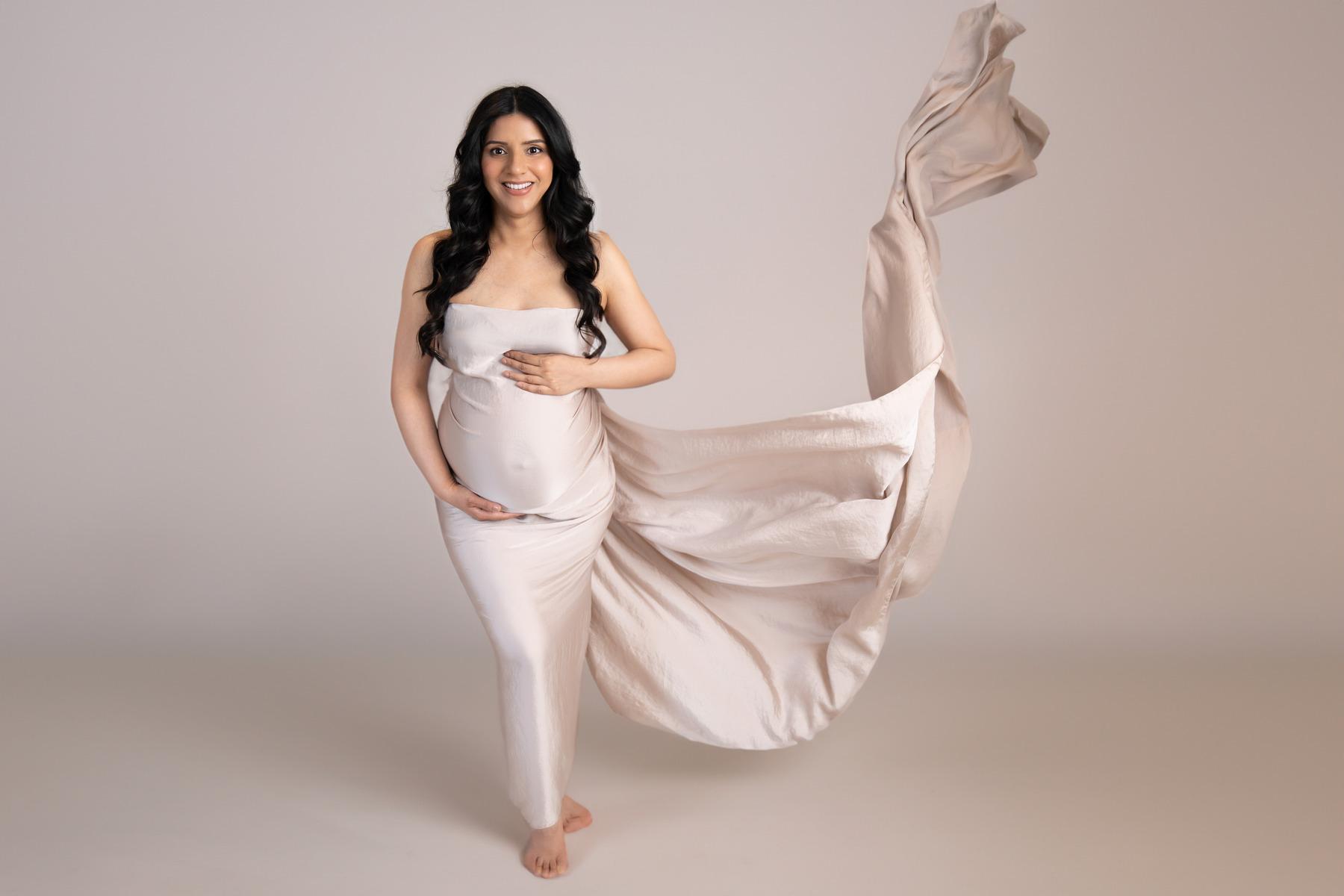 "A glowing pregnant woman wrapped in cream silk, captured by Ceire Rhein, Dublin's maternity photographer."